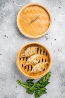 Steamed Japanese Gyoza Dumplings with pork meat and vegetables in bamboo steamer. grey background. top view photo