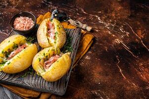 Jacket potatoes baked with cheese, herbs and butter. Dark background. Top view. Copy space photo