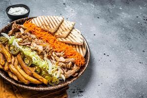 Chicken Shawarma Doner kebab on a plate with french fries, vegetables and salad. Gray background. Top view. Copy space photo