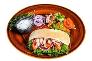 Pita salad with roasted chicken and vegetables on a plate. Isolated on white background. photo
