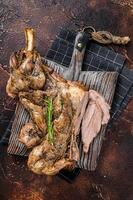 Slow Cooked grilled lamb mutton shoulder meat with herbs and spices on wooden board. Dark background. Top view photo