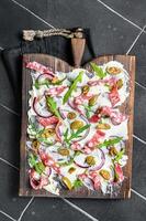 Butterboard, Butter Board with olives, onion, arugula, capers and tomato. Black background. Top view photo