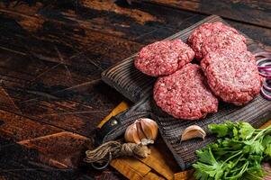 Fresh Raw burger patty, mince beef Meat, uncooked meat cutlets. Wooden background. Top view. Space for text photo