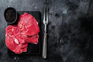 Raw Mutton fillet steaks from leg, uncooked lamb meat. Black background. Top view. Copy space photo