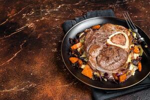 Osso buco cross cut veal shank with mashed potato on a plate. Dark background. Top view. Copy space photo