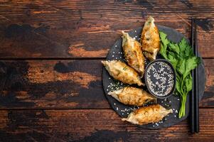 Fried Gyoza on plate with sauce, Japanese Dumplings with shrimps and vegetables. wooden background. top view photo