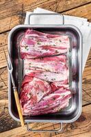Marinated lamb shanks with herbs, spices and thyme. Mutton meat ready for cooking. Wooden background. Top view photo
