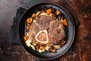 Osso buco cross cut veal shank with mashed potato on a plate. Dark background. Top view photo