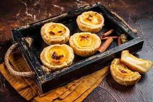 Belem cakes or Pasteis de Belem, Portuguese pastel de Nata Custard Tarts. Dark background. Top view photo