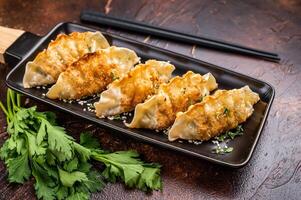 Fried Korean Dumplings on plate with sauce, Dumplings with shrimps and vegetables. brown background. top view photo