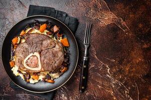 Osso buco cross cut veal shank with mashed potato on a plate. Dark background. Top view. Copy space photo
