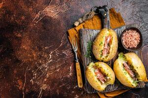 Jacket potatoes baked with cheese, herbs and butter. Dark background. Top view. Copy space photo