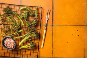 Grilled Broccolini Sprouts with garlic. Orange background. Top view. Copy space photo