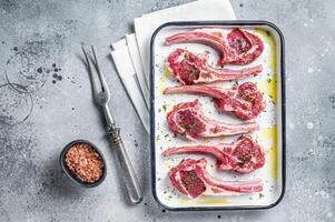 Ready for cooking raw lamb chop steaks with spices and herbs. Gray background. Top view photo