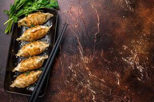 Fried Korean Dumplings on plate with sauce, Dumplings with shrimps and vegetables. brown background. top view photo