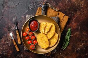 Roast Hash brown potato, Vegetable fritters in a plate with tomato sauce. Dark background. Top view photo