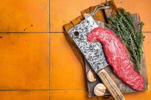 Fresh Raw Machete beef meat steak or hanging tender cut on butcher cutting board. Orange background. Top view. Copy space photo