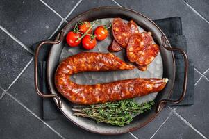 Sliced Chorizo sausage, slices of dry cured pork with herbs and spices. Black background. Top view photo
