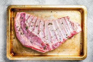 Marinated lamb mutton ribs with herbs and thyme in baking dish. White background. Top view photo