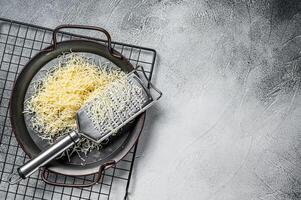 Grated cheese for cooking in a steel tray with grater. White background. Top view. copy space photo
