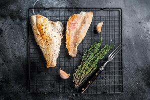 Grilled sea red perch fillet, Snapper fish on a rack. Black background. Top view photo