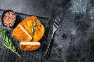 Schnitzel Cordon bleu fillet cutlet with ham and cheese. Black background. Top view. Copy space photo