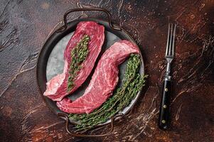 Raw Bavette or Sirloin flap beef meat steak with thyme. Dark background. Top view photo