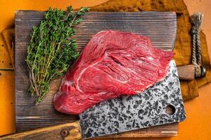 Piece of Raw beef meat for stew with herbs on butcher cutting board. Orange background. Top view photo