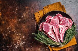 Raw lamb chops, fresh mutton meat cutlets on a ribs. Dark background. Top view. Copy space photo