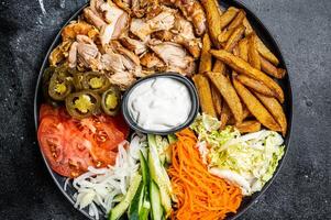 Shawarma Doner kebab on a plate with french fries and salad. Black background. Top view photo