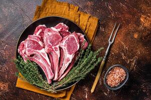 Raw lamb chops, fresh mutton meat cutlets on a ribs. Dark background. Top view photo
