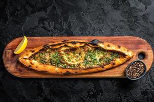 Turkish pide pie with beef meat and vegetables. Black background. Top view photo