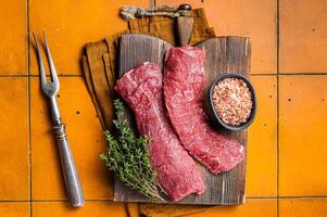 Butcher table with Raw lamb tenderloin Fillet, Mutton loin Meat with thyme. Orange background. Top view photo
