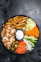 Shawarma Doner kebab on a plate with french fries and salad. Black background. Top view photo
