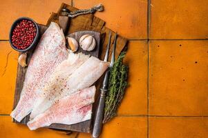 Uncooked ocean red perch fillet, redfish with herbs and spices. Orange background. Top view. Copy space photo
