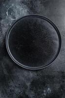Empty black craft plate on table. Table setting. Black background. Top view. Copy space photo