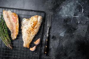 Grilled sea red perch fillet, Snapper fish on a rack. Black background. Top view. Copy space photo