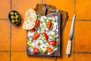 Trendy Butter Board with olives, onion, arugula, capers and tomato, Butterboard. Orange background. Top view photo