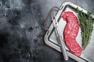 Raw fresh meat Steak Machete, skirt with thyme on steel tray. Black background. Top view. Copy space photo