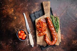 Dry cured Spanish Chorizo sausage, slices of meat with herbs and spices. Dark background. Top view photo