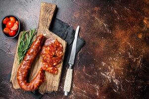 Dry cured Spanish Chorizo sausage, slices of meat with herbs and spices. Dark background. Top view. Copy space photo