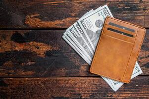 One hundred dollar bill in a brown leather wallet with credit cards. Brown background. Top view. Copy space photo