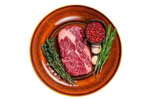 Black angus rib eye raw beef steak on a rustic plate. Isolated on white background. photo