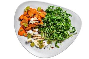 Grilled pumpking warm salad with arugula, walnuts and brie cheese. Isolated on white background. photo