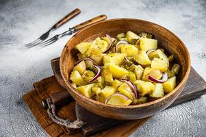 Bowl of warm potato salad with bacon, German Kartoffelsalat. White background. Top view photo