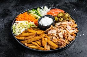 Shawarma Doner kebab on a plate with french fries and salad. Black background. Top view photo