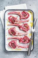 Ready for cooking raw lamb chop steaks with spices and herbs. Gray background. Top view photo