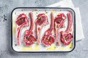 Ready for cooking raw lamb chop steaks with spices and herbs. Gray background. Top view photo