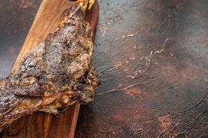 Roast lamb leg meat with herbs and spices on a cutting board. Dark background. Top view. Copy space photo
