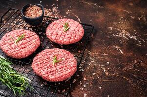 Raw burger cutlet from beef meat with spices and rosemary ready for cooking. Dark background. Top view. Copy space photo